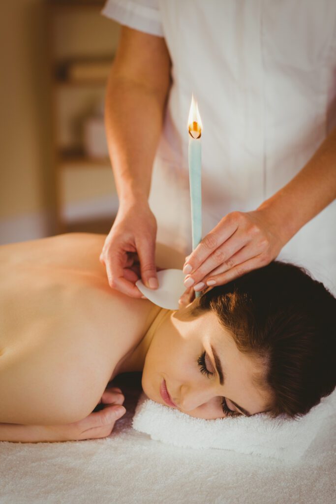 Young woman getting ear candling treatment in therapy room